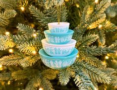 three blue bowls stacked on top of each other in front of a christmas tree with lights