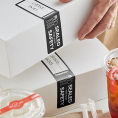 two boxes with labels on them are being held by someone's hand over a table