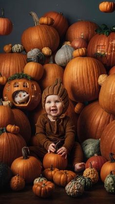 a baby sitting in front of a pile of pumpkins