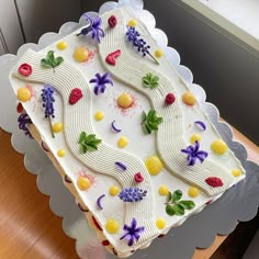 a decorated cake sitting on top of a wooden table next to a white window sill