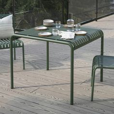 an outdoor table with two chairs and plates on it, sitting on a wooden deck