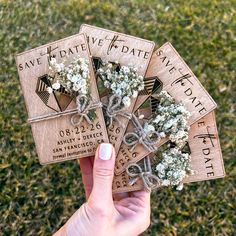 four tags with flowers tied to them in someone's hand on the grass outside