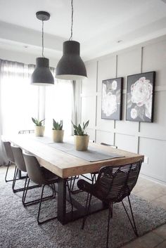 a dining room table with four chairs and two plants on the table in front of it