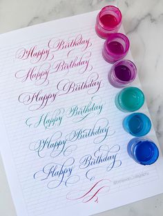 a sheet of paper that has some writing on it with different colored paints in front of it