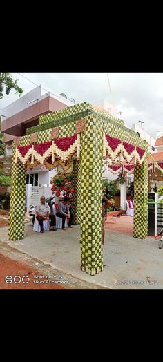 an elaborately decorated gazebo on the side of a road with people sitting under it