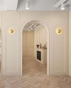 an empty room with white walls and wood flooring is seen through two archways