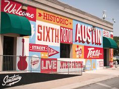 a building with many different signs painted on it's side and the name of the store