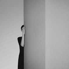 black and white photograph of a woman hiding behind a wall