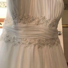 a white wedding dress with silver beading on the waistline and belt is displayed in front of a mirror