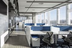 an empty office with blue and white cubicles on the walls, windows, and desks