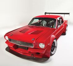 a red mustang muscle car sitting on top of a white floor