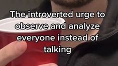 a man holding a red cup with the caption, the involved urge to observe and analize everyone instead of talking