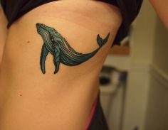 a woman's stomach with a tattoo of a whale on it and waves coming out of the water