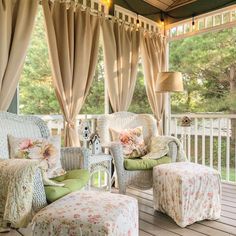 a covered porch with wicker chairs and foot stools on the deck, surrounded by curtains