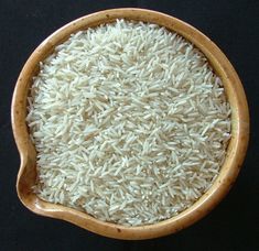 white rice in a wooden bowl on a black surface