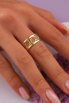 a woman's hand wearing a gold ring with initials on the middle and bottom