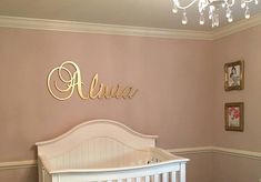 a baby's room with a crib, chandelier and pictures on the wall