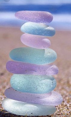 a stack of glass pebbles sitting on top of a sandy beach next to the ocean