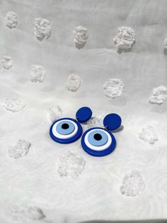 two blue and white eyeballs sitting on top of a bed with white sheets