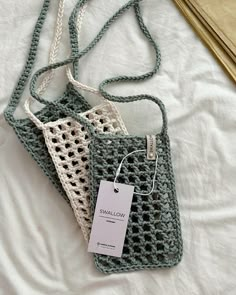 two crocheted purses sitting on top of a white bed next to each other