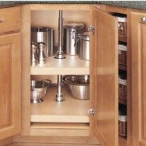 an open cabinet in the corner of a kitchen with wooden floors and cupboards filled with pots and pans