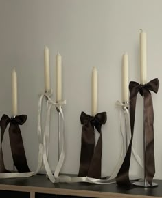 candles are lined up on a shelf with ribbons