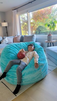 a young boy laying on top of a large bean bag chair in a living room