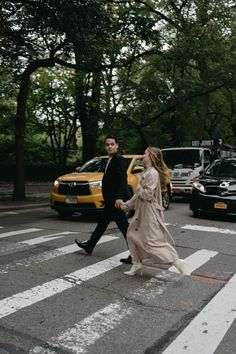 a man and woman walking across a cross walk