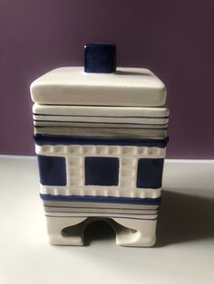 a white and blue container sitting on top of a table next to a purple wall