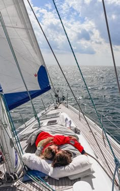 two people laying on the back of a sailboat