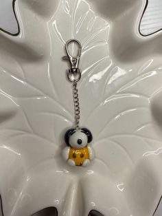 a white flower with a black and yellow bear keychain on it's side