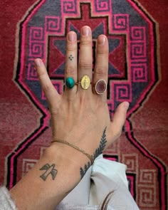 a woman's hand with three different rings on her left wrist and two fingers