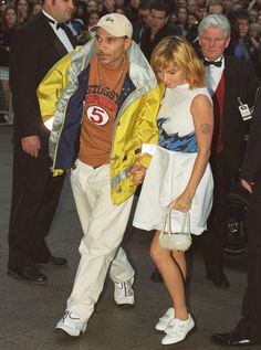 a man and woman are walking together in front of a large crowd at an event