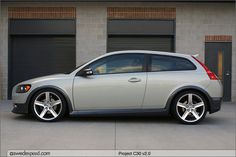 a silver car parked in front of a building with two garage doors on it's side