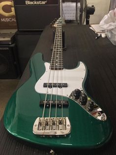 a green bass guitar sitting on top of a table