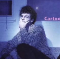 a man sitting on top of a couch in front of a tv screen with the caption cartoons