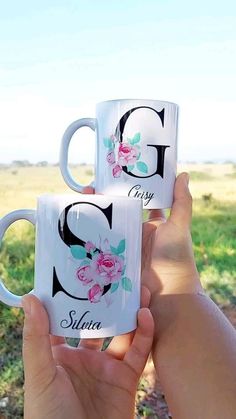 two people holding up coffee mugs with the letters g and s painted on them