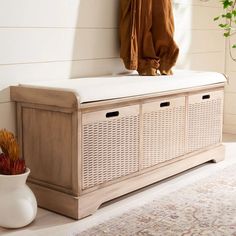 a white bench sitting next to a vase and coat rack