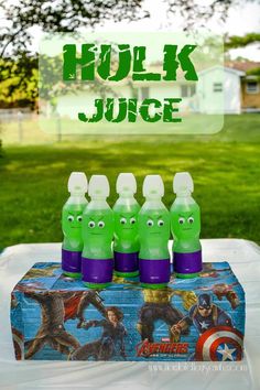 some green juice bottles sitting on top of a table in front of a grass field