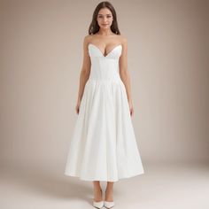 a woman is wearing a white dress with straps on the waist and heels on the side