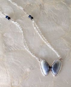 a necklace with two seashells hanging from it's sides on a marble surface