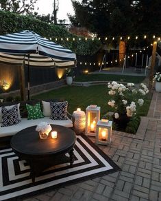 an outdoor seating area with lit candles on the table and in the background is a gazebo