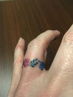 a woman's hand with a flower tattoo on it, and the ring has blue flowers