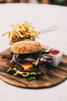 a cheeseburger with fries and ketchup on a cutting board