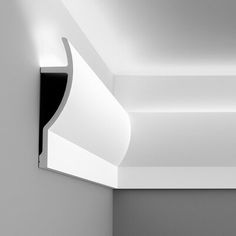 a black and white photo of a corner in a room with light coming from the ceiling