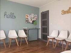 three white chairs in a room with wood floors and a sign on the wall above them