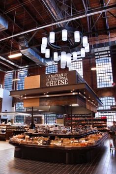 the inside of a restaurant with lots of food on display and lights hanging from the ceiling