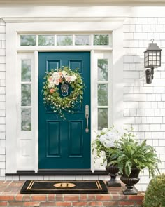 a blue front door with a wreath and two planters on the steps next to it