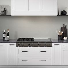 a stove top oven sitting inside of a kitchen next to white cabinets and counter tops