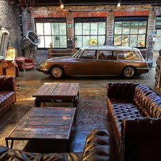 an old car is parked in a warehouse with leather couches and tables around it